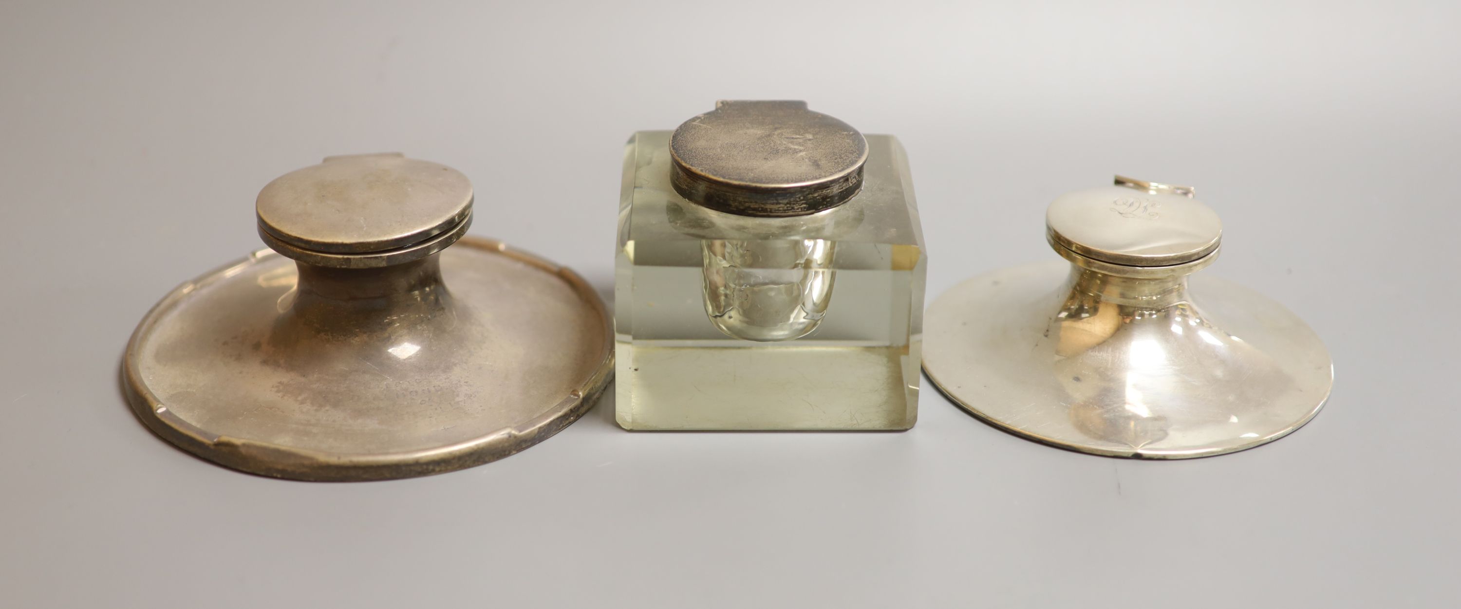 Three assorted silver mounted inkwells including two capstan, largest 15.2cm.